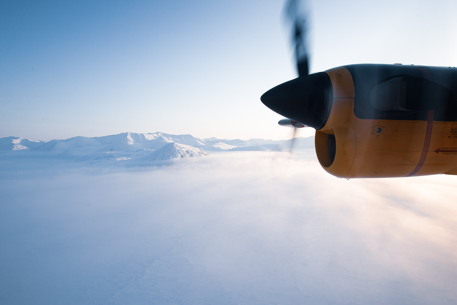 RCAF CC-138 Twin Otter in flight, propeller arc visible against pale Arctic sky. Ellesmere Island, High Arctic, Canada, Op NUNALIVUT 2008.