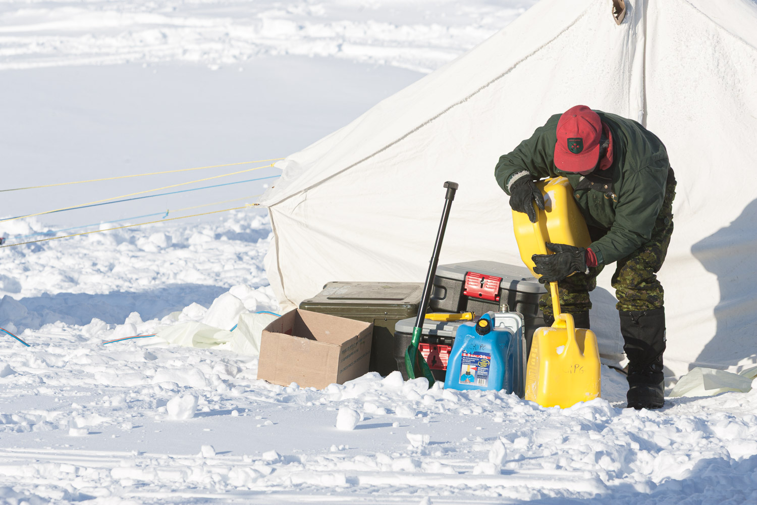 Canadian Ranger pouring fuel iat temporary camp with tents on the ice. Ellesmere Island, High Arctic, Canada, Op NUNALIVUT 2008.