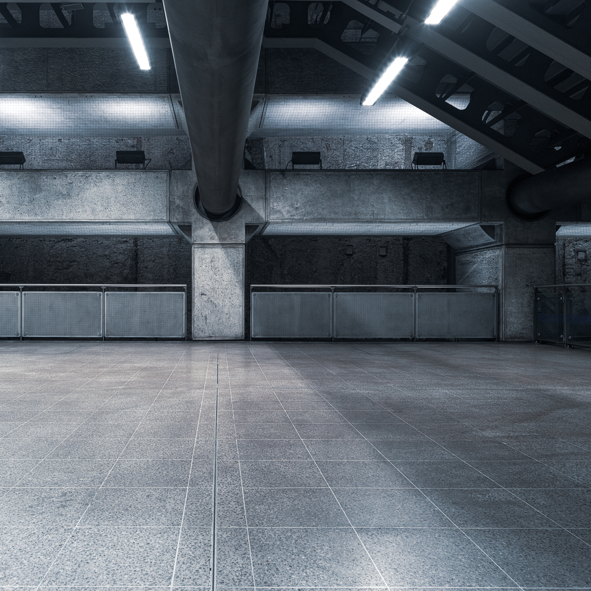 Westminster Station concourse with a large overhead ventilation pipe and tiled floor.