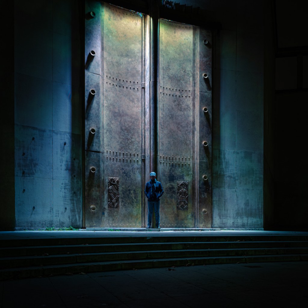 Figure standing before monumental metal doors at the Museum of Modern Art in Paris.