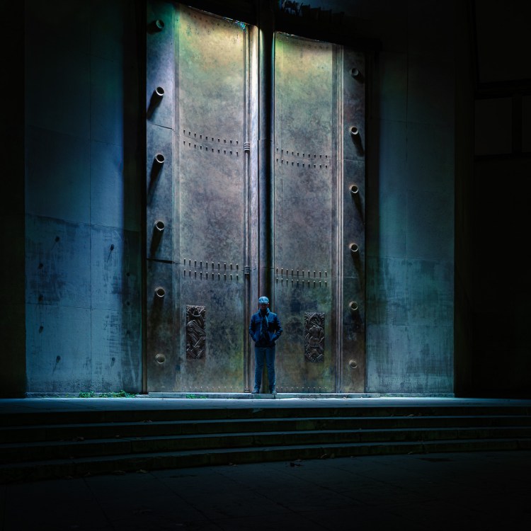 Figure standing before monumental metal doors at the Museum of Modern Art in Paris.