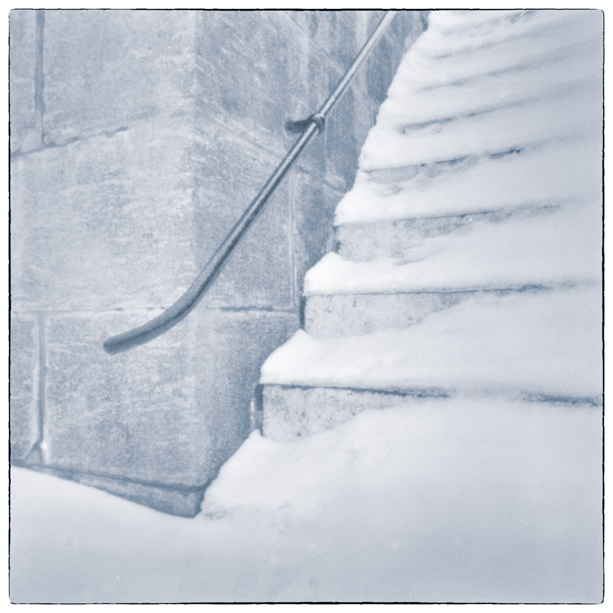 Long-exposure black and white photograph of snow-covered concrete steps and a metal handrail at Old Slys Lock in Smiths Falls, Ontario.
