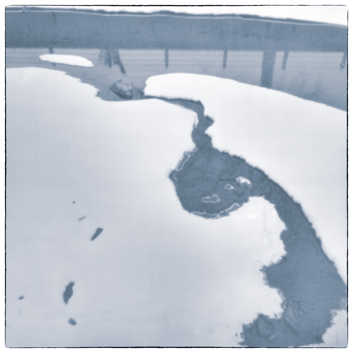 Long-exposure black and white photograph of a partially frozen drained lock basin at the Smiths Falls Combined Lockstation, with exposed ice and dark channels of water.