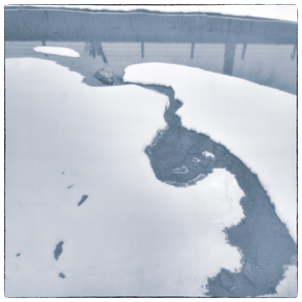 Long-exposure black and white photograph of a partially frozen drained lock basin at the Smiths Falls Combined Lockstation, with exposed ice and dark channels of water.