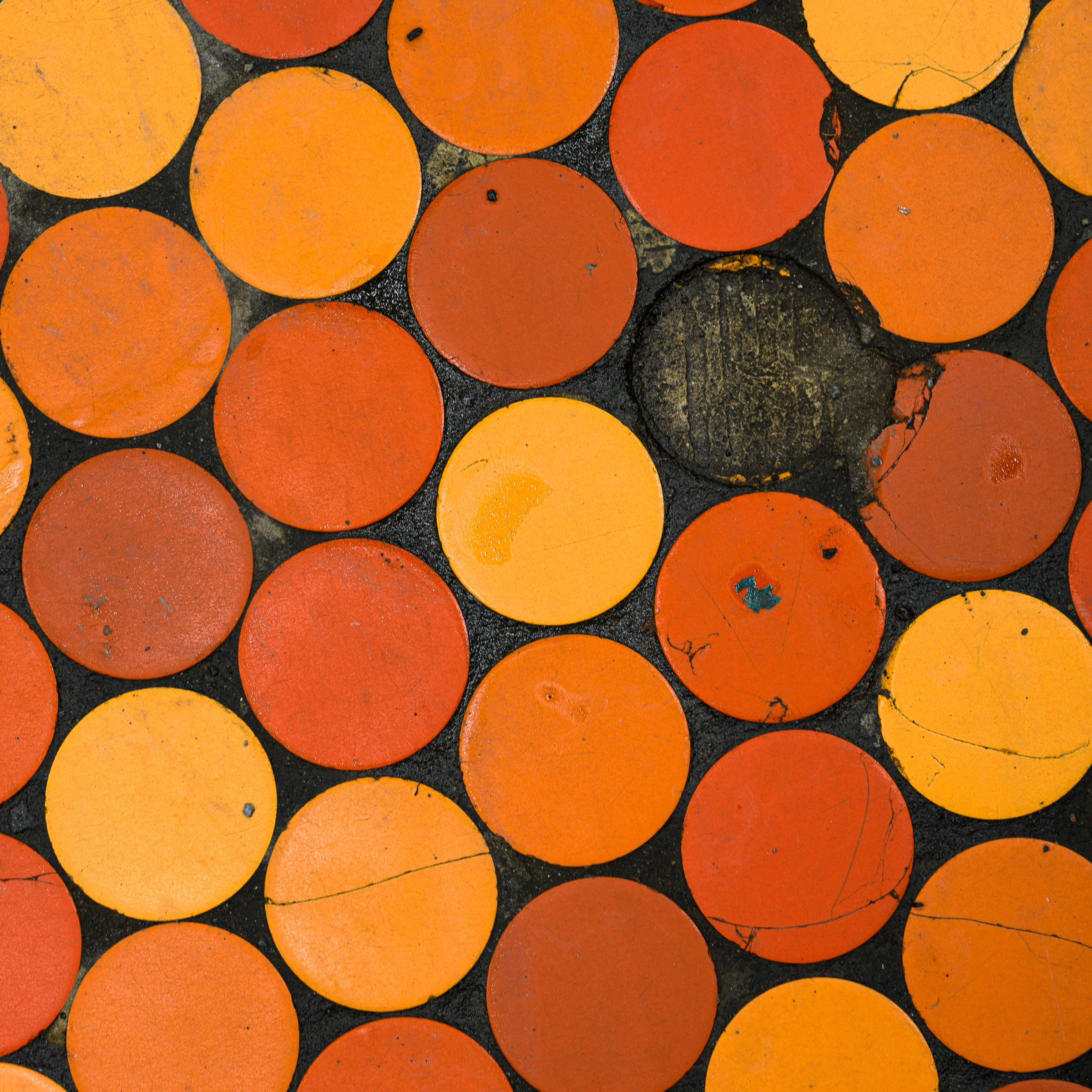 Colour photograph of circular orange and yellow platform tiles at Lionel-Groulx station in the Montréal Métro, with one tile missing from the pattern.