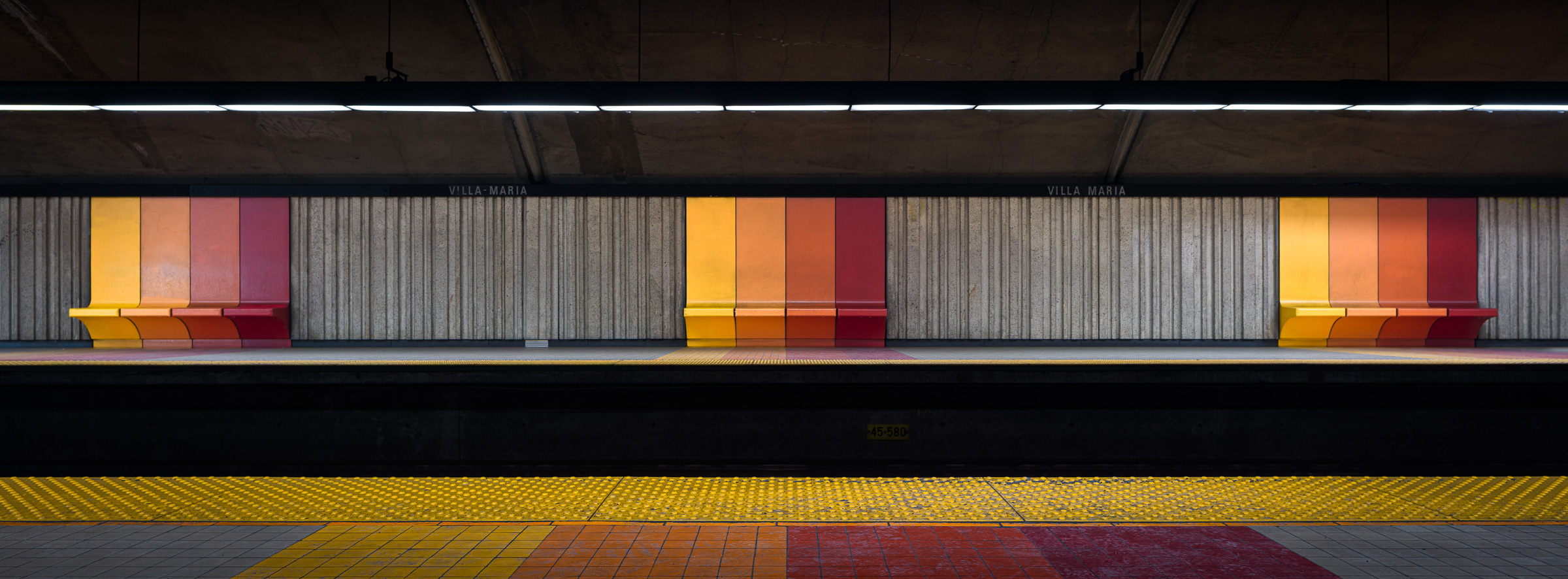 Panoramic colour photograph of platform seating at Villa-Maria station in the Montréal Métro, viewed from across the tracks.