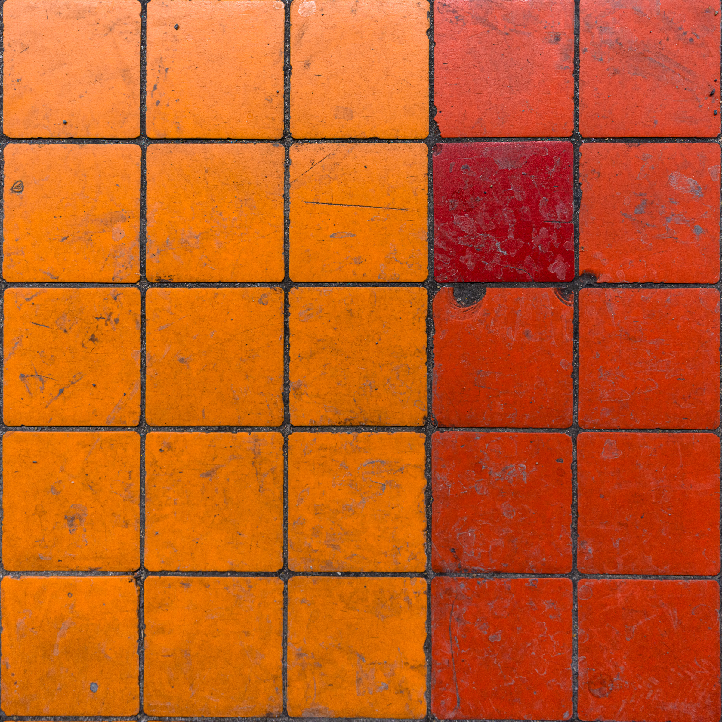 Colour photograph of worn orange and red platform tiles at Villa-Maria station in the Montréal Métro, including a single red tile interrupting the pattern.