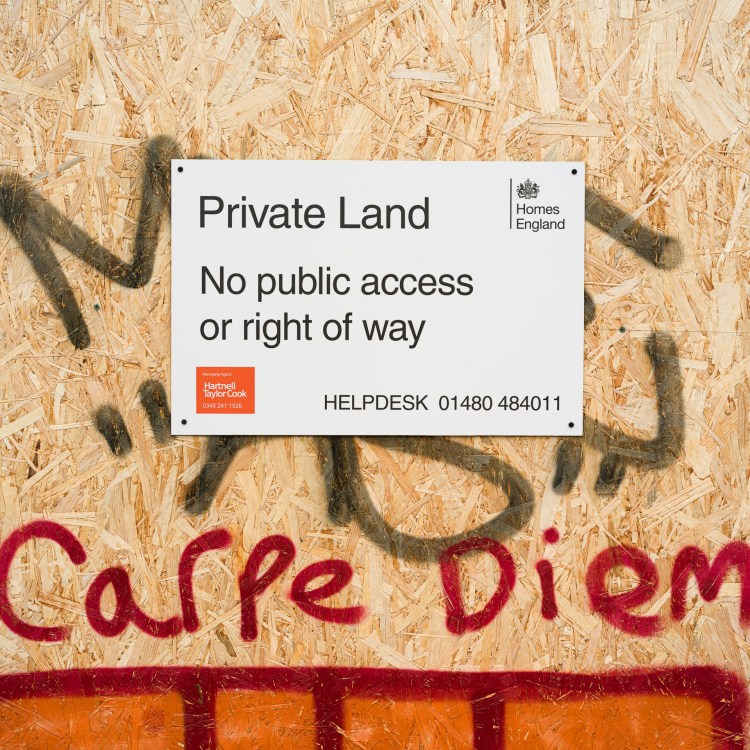 “Private Land” and “No public access or right of way” sign marked with red “Carpe Diem” graffiti.