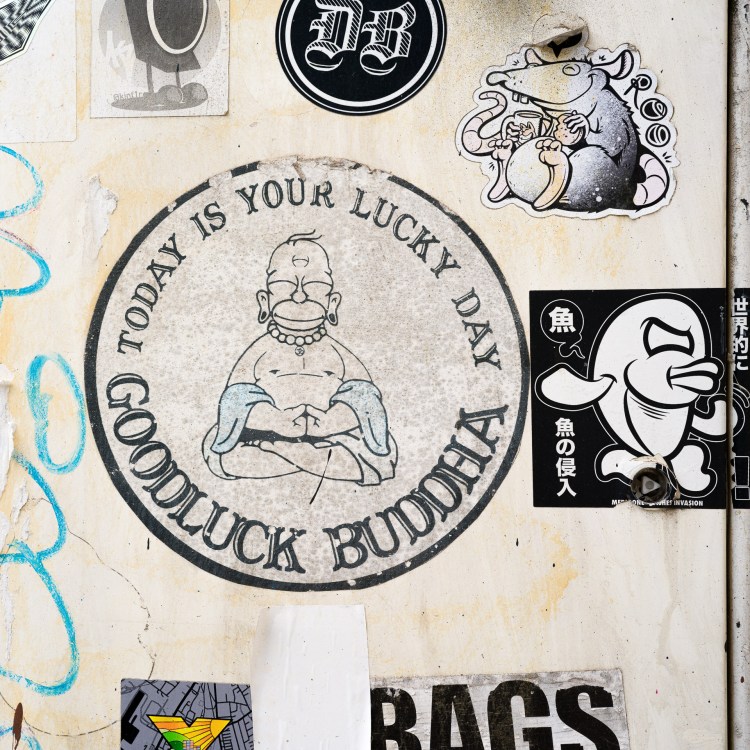 Street artwork depicting Homer Simpson seated in a Buddha-like pose on a wall in Bristol.