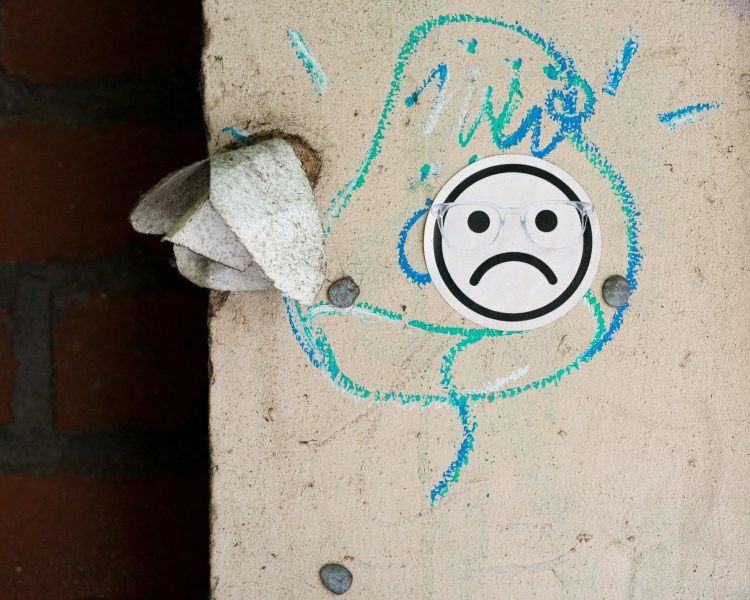 Frowning face graphic wearing translucent glasses on a wall or street surface in Bristol.