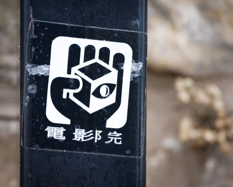 Sticker combining a cube, eye and hand motif with East Asian characters in Bristol.