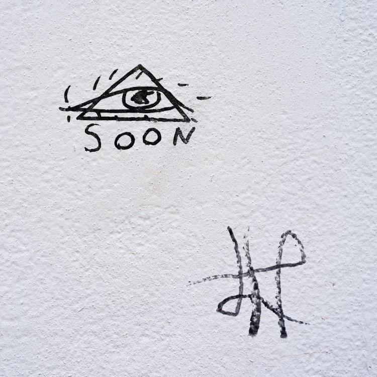 Street artwork combining an eye and triangle motif with the word “Soon” in Bristol.