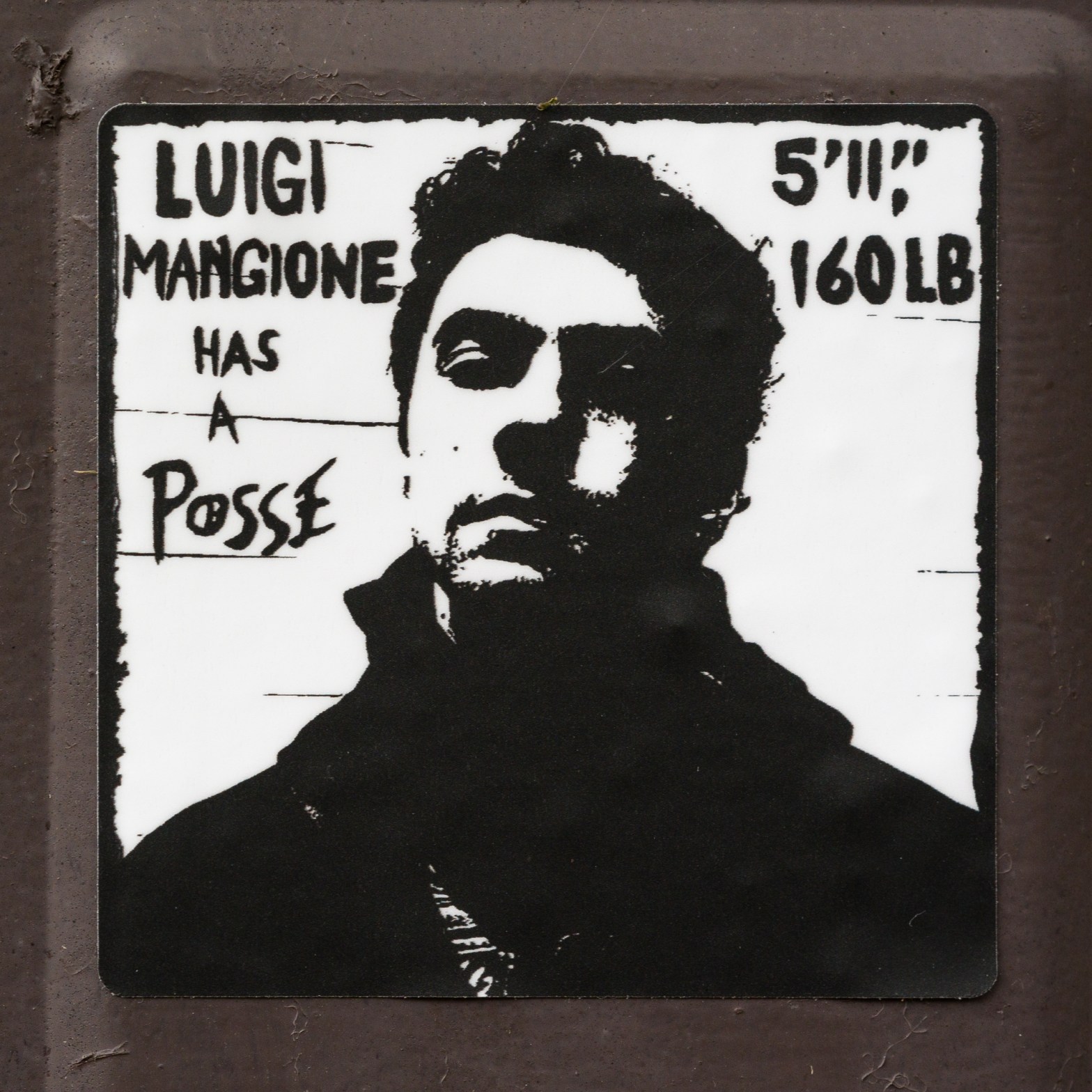 Black-and-white “Luigi Mangione Has a Posse” sticker on a utility box in Kingston, Ontario.