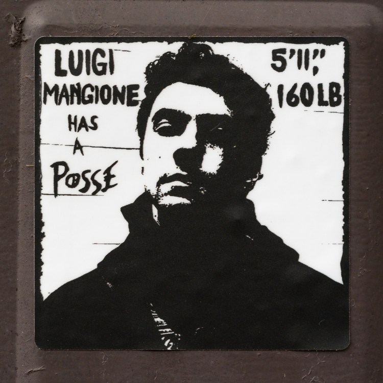 Black-and-white “Luigi Mangione Has a Posse” sticker on a utility box in Kingston, Ontario.