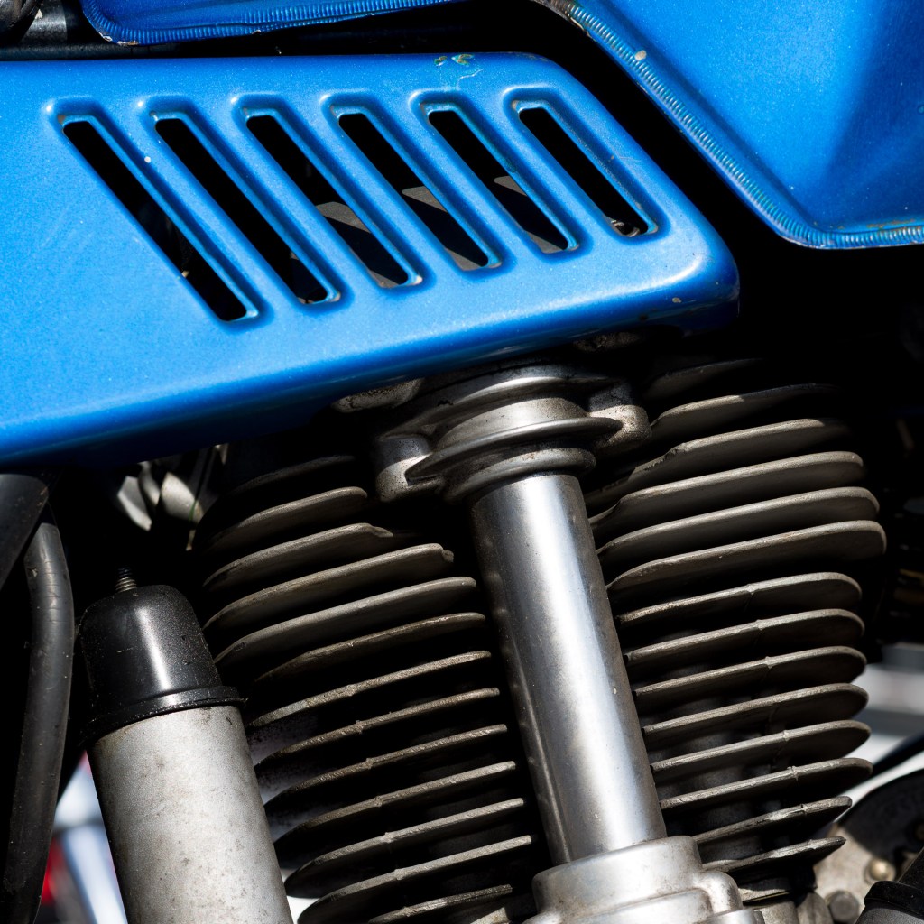 Close-up of blue bodywork, engine fins and suspension components on a 1978 Ducati 900 GTS motorcycle.