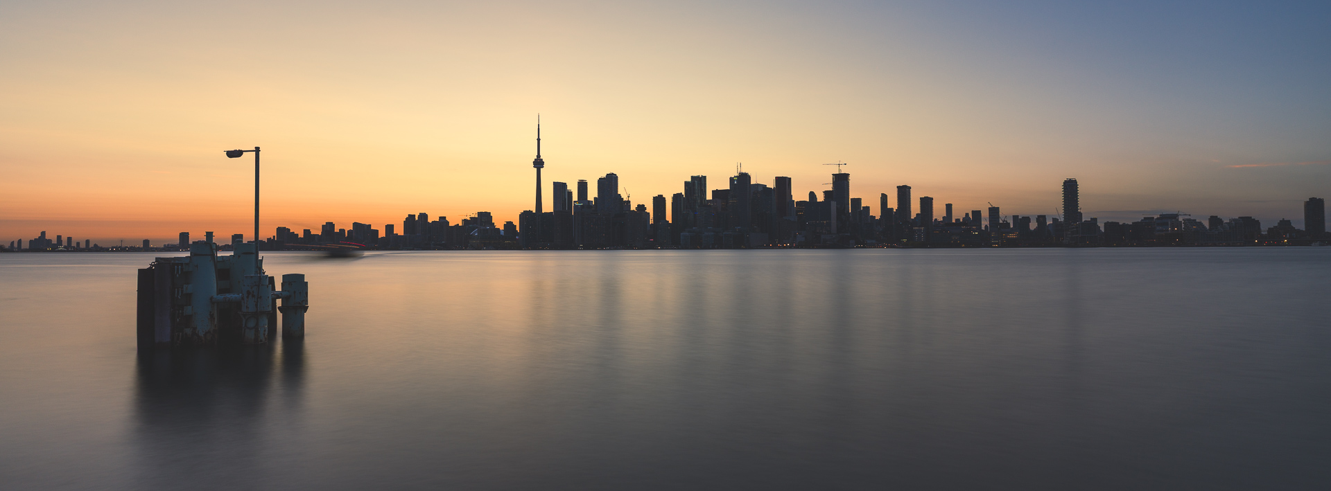Toronto skyline at sunset viewed across the harbour from a Toronto Islands ferry terminal.