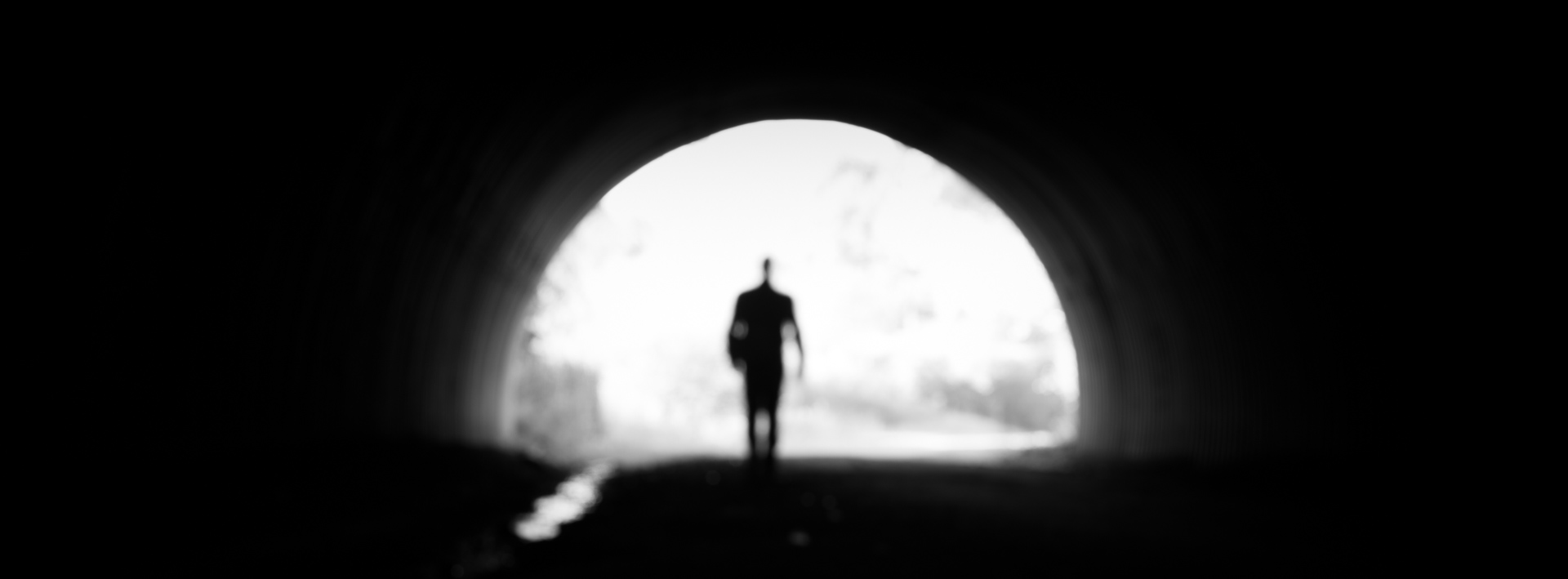 Deliberately out-of-focus black-and-white self-portrait of a figure walking through an underpass on the K&P Trail.