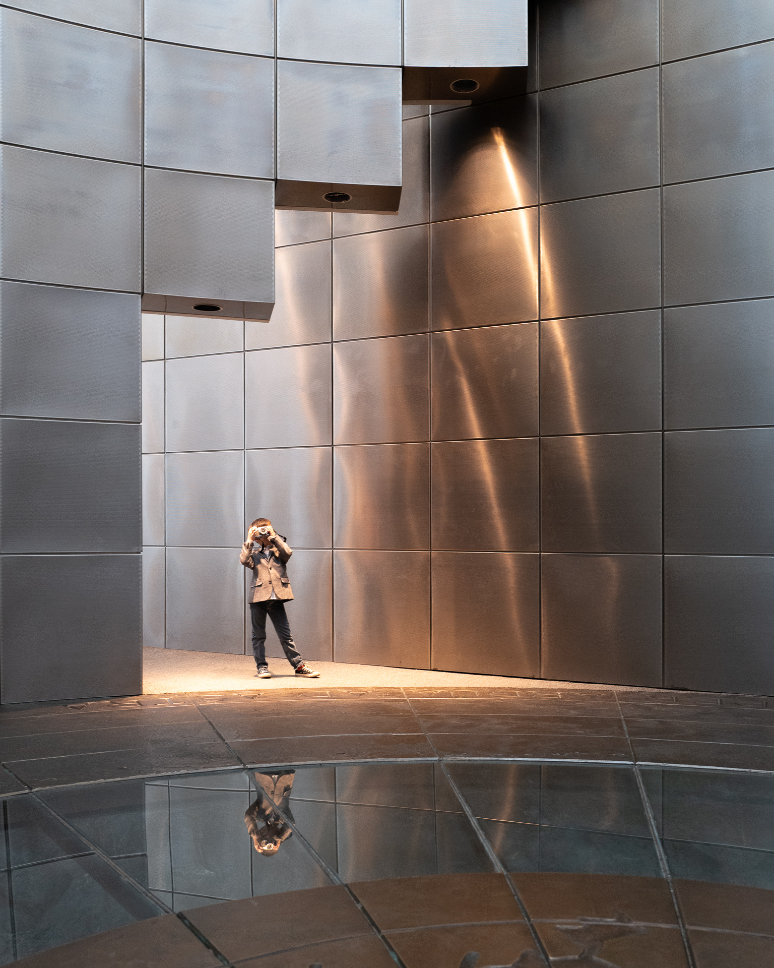 Young boy taking a photograph beneath dramatic lighting at the entrance to the RCAF Hall of Tribute in Ottawa.