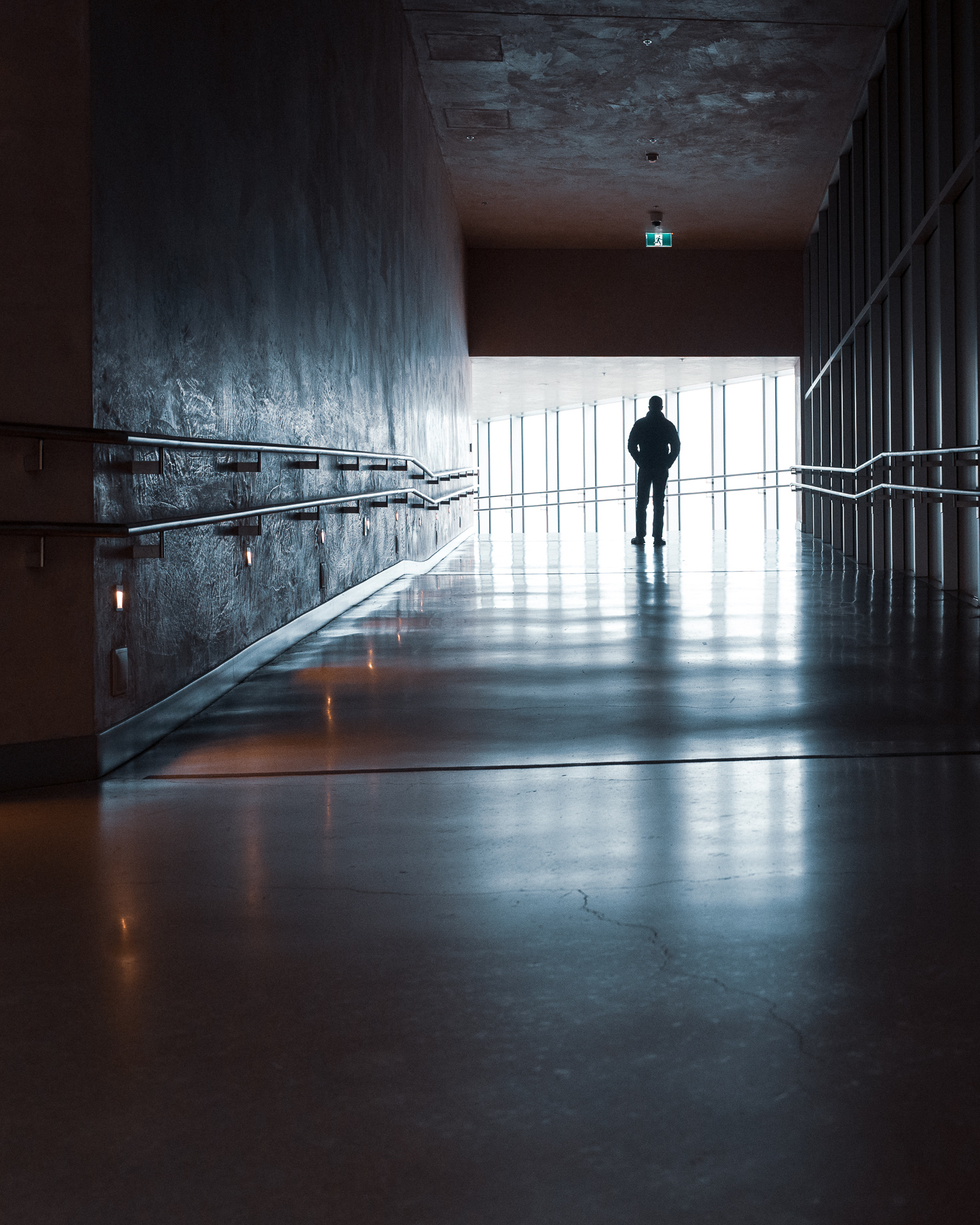 Self-portrait of a silhouetted figure standing at the bright end of a dark ramp inside the Canadian Museum for Human Rights in Winnipeg.