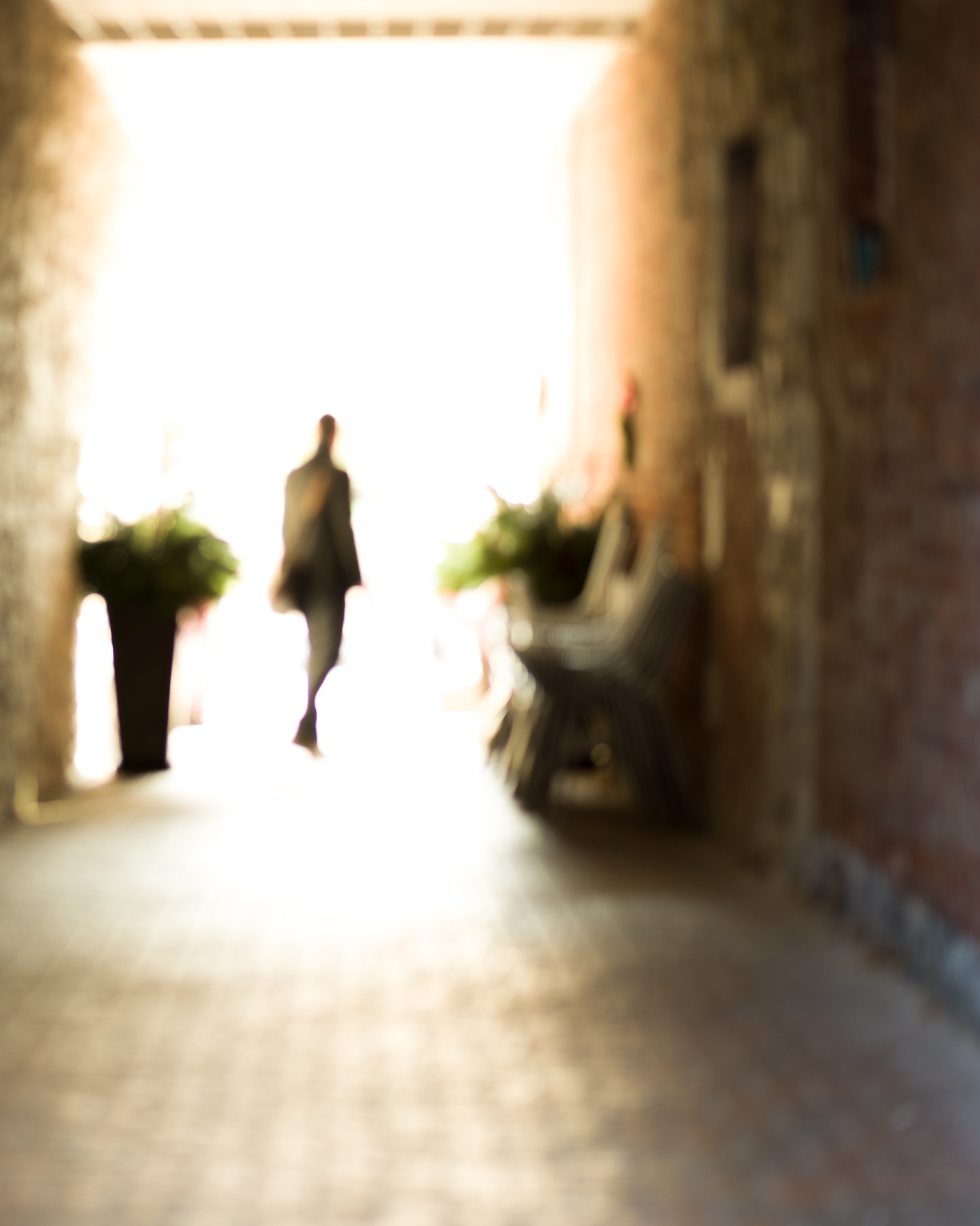 Deliberately out-of-focus self-portrait of a solitary figure moving through a bright alley passageway.